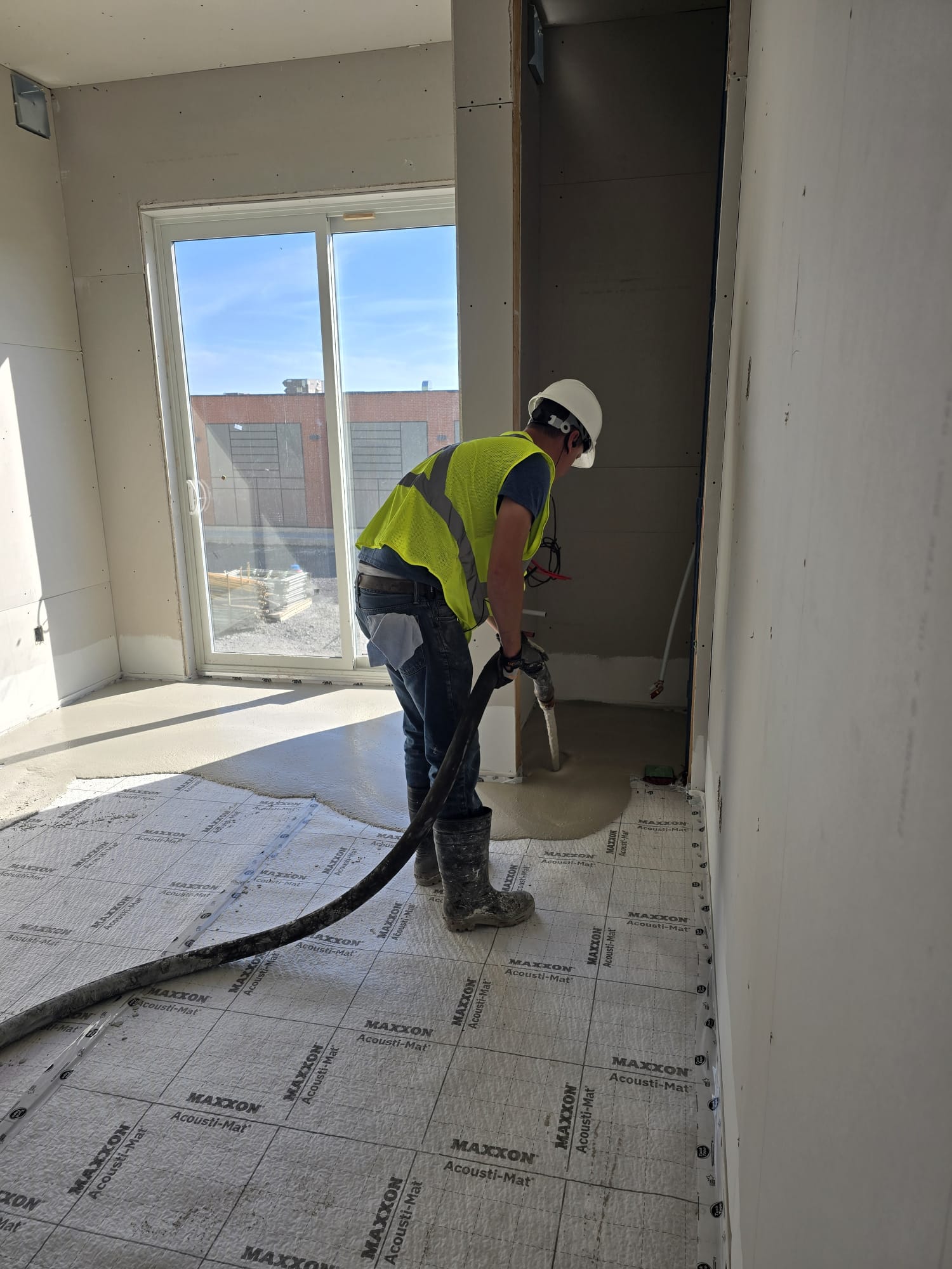 Worker pumping compound over Maxxon Acousti-Mat during floor prep