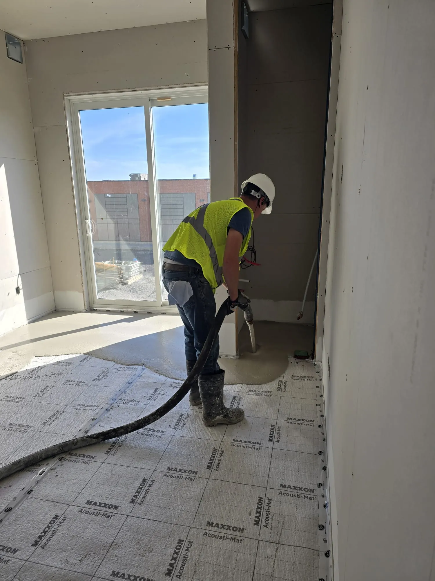 Worker pumping compound over Maxxon Acousti-Mat during floor prep